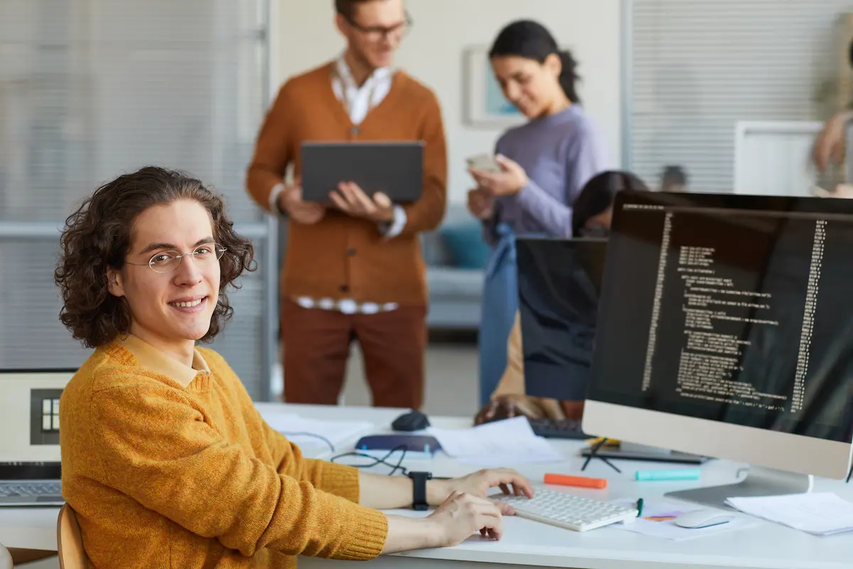 portrait-young-it-developer-looking-camera-smiling-while-using-computer-with-code-screen-software-production-studio-copy-space portrait-young-it-developer-looking-camera-smiling-while-using-computer-with-code-screen-software-production-studio-copy-space