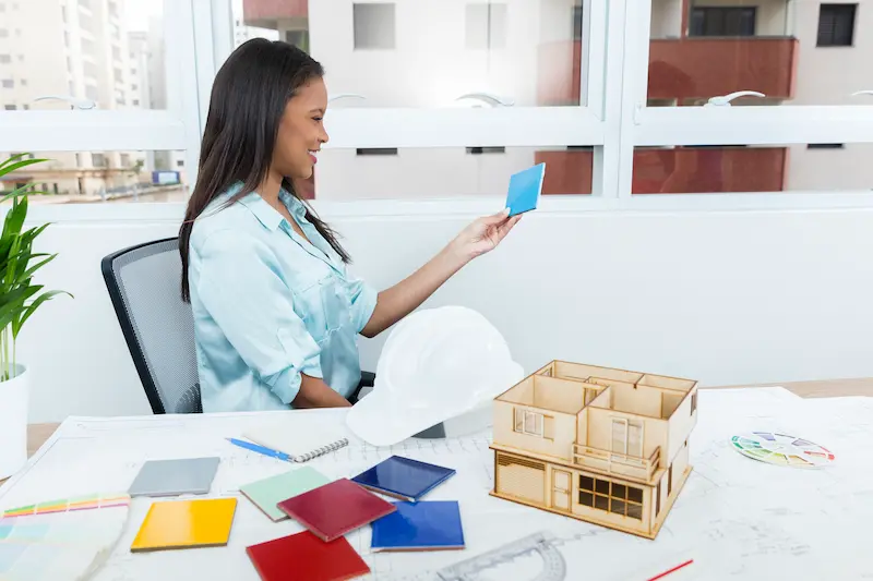 smiling-african-american-lady-chair-near-plan-model-house-table smiling-african-american-lady-chair-near-plan-model-house-table